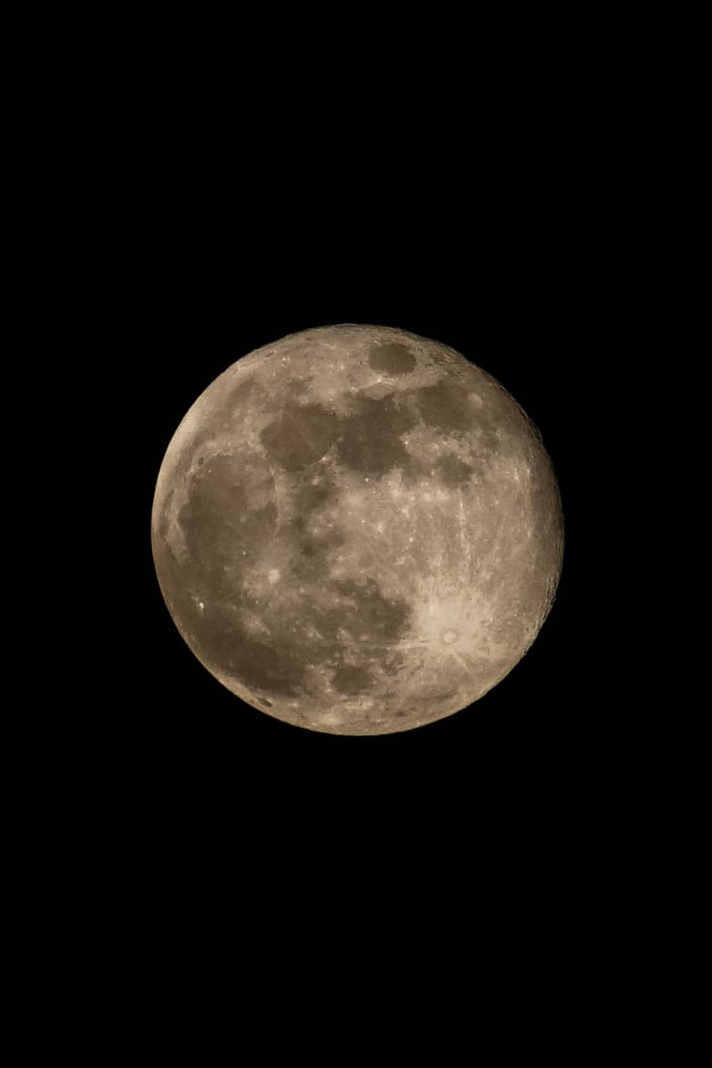 Full moon in warm golden tones centered on a black sky, dark lunar maria and bright ray craters clearly visible