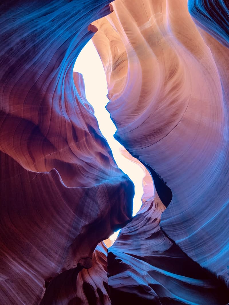 Zigzag sliver of white sky splitting deep blue and orange sandstone walls inside Antelope Canyon