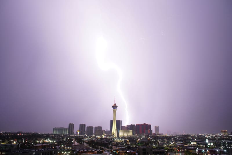 Thick blinding lightning bolt snaking from a bright lavender sky to the skyline just right of the Strat tower, Las Vegas