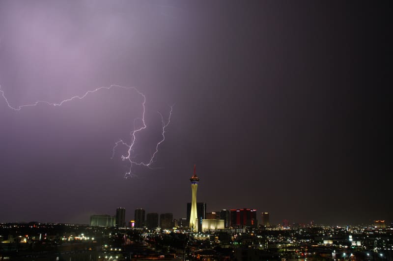 Crawler lightning branching sideways through a purple storm sky up and to the left of the Strat tower over Las Vegas