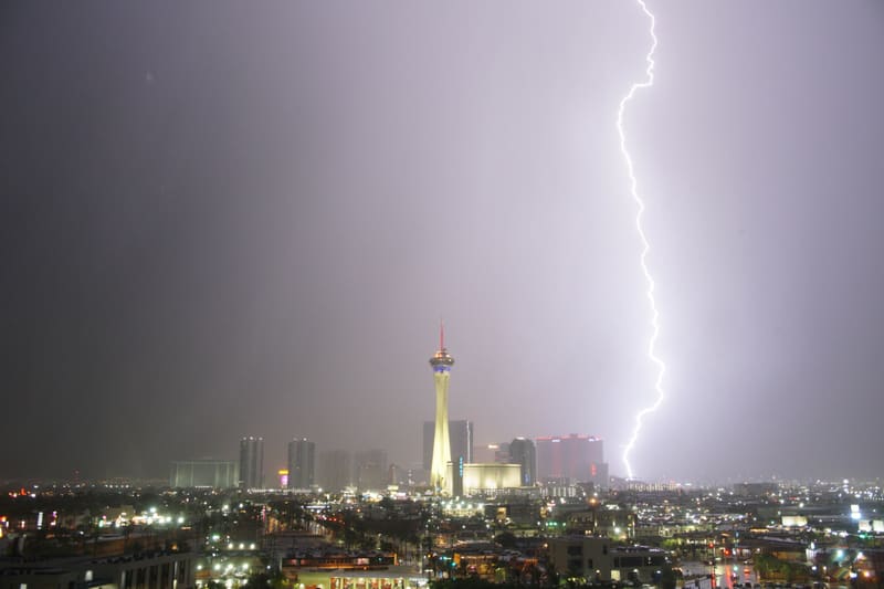 Thick, blinding lightning bolt strikes to the right of the Strat tower, washing the Las Vegas night sky pale grey