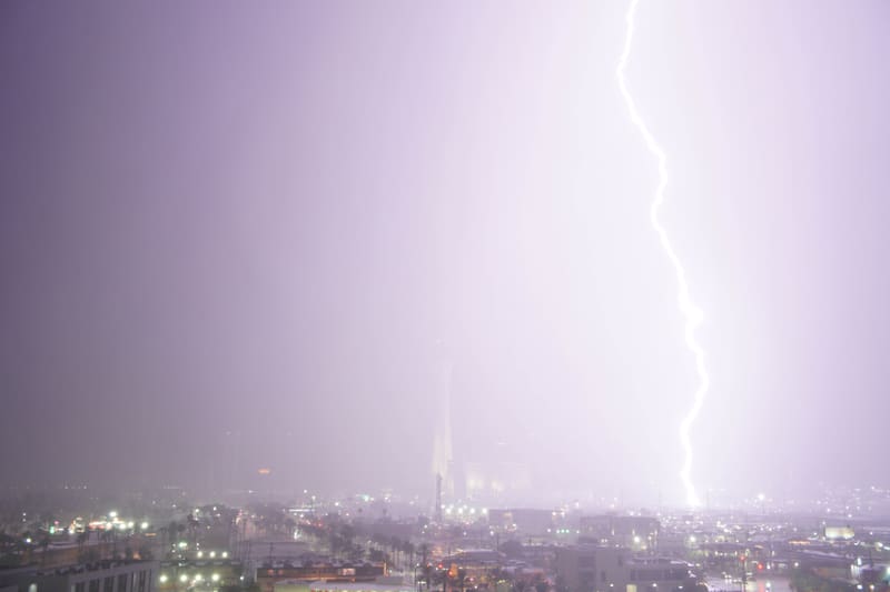 Overexposed lightning bolt washing a pale lavender rainy sky white to the right of the faint Strat tower in Las Vegas