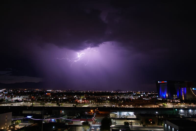 Tangled web of intracloud lightning glows in a purple storm sky over Las Vegas, World Market Center lit blue at right