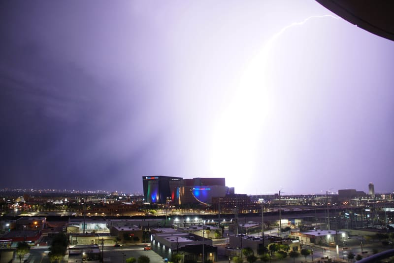 Blinding white lightning flash inside storm clouds over downtown Las Vegas, a thin bolt tip visible at upper right